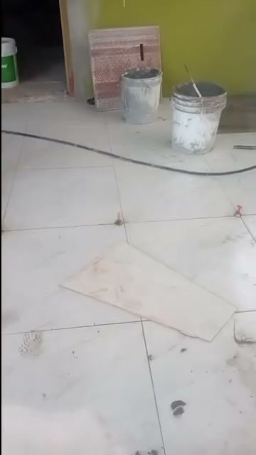 Floor tiles set out mid-job with buckets of mortar against a green wall